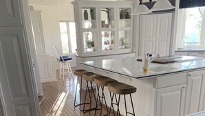 A kitchen with a central island, bar stools, and white cabinetry. - 80-acre Mountaintop Villa with Spectacular Views (Coarsegold)