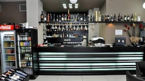 A bar area with shelves of liquor bottles, a Coca-Cola refrigerator, and a counter with a computer. - Hotel Vila Lule (Durrës)