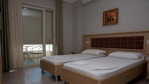 A hotel room with two single beds, a balcony with a chair, and a framed picture on the wall. - Hotel Vila Lule (Durrës)