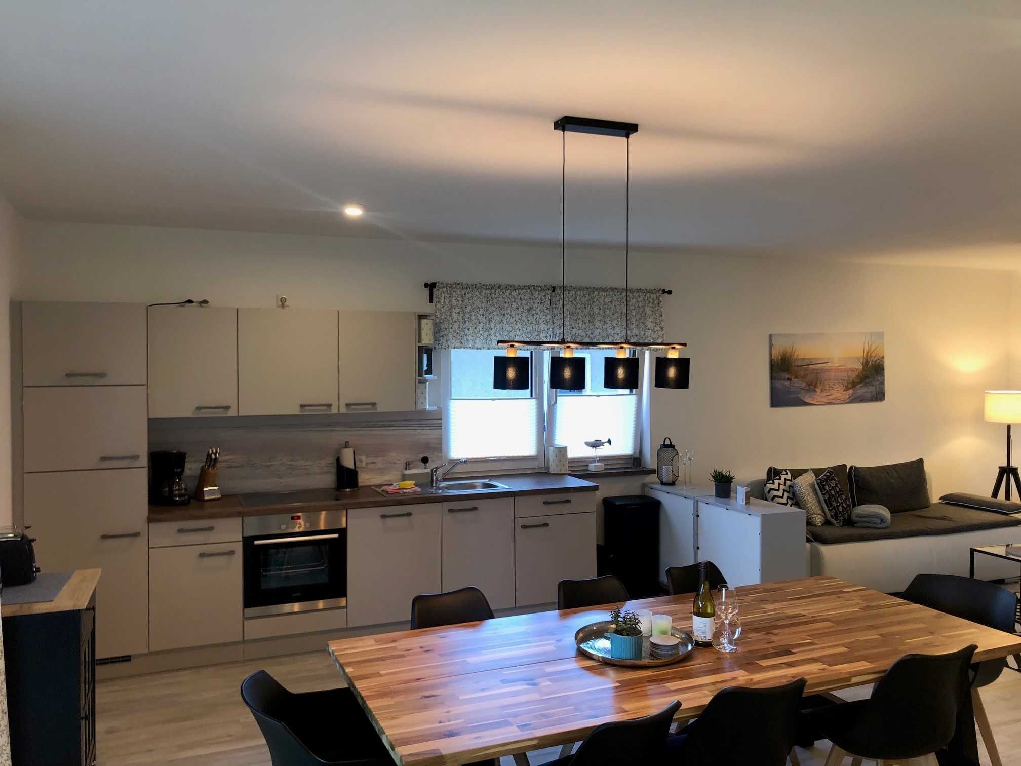 Una cocina moderna con armarios blancos, una mesa de comedor de madera y un ventanal grande.