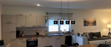 Una cocina moderna con armarios blancos, una mesa de comedor de madera y un ventanal grande.