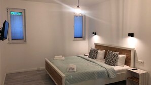 Un dormitorio moderno con cama, mesitas de noche y dos luces fijadas a la pared.