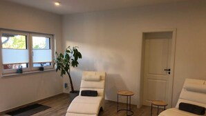 Una habitación con dos sillones reclinables, una planta en maceta, una mesita y una puerta.