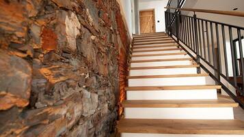 Un escalier avec des marches en bois et un mur en pierre d’un côté.