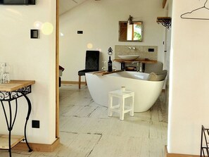 A modern bathroom with a freestanding bathtub, a small stool, a mirror, and a sink. - Zur Linde - Roiderhof am Irrsee (Laiter)