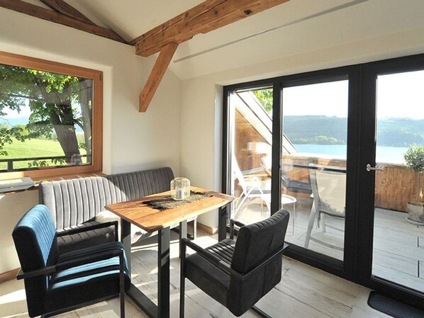 A room with a wooden ceiling, a sofa, a table, and a view of the outdoors.