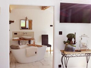 Un baño moderno con una bañera independiente, un tocador con espejo y una planta en maceta.