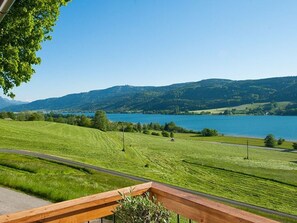 Una vista panoramica su un lago con un pontile di legno e una strada che si snoda attraverso un paesaggio verde.