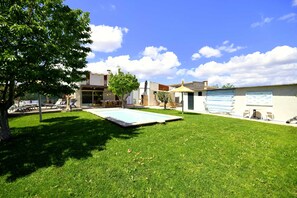 A backyard with a swimming pool, a tree, and a building with a garage.