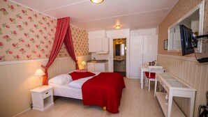 A bedroom with a bed, bedside table, lamp, and a mirror. - Apartment Süd Terasse 45m² (Rømø)
