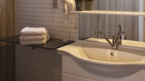 A bathroom with a white sink, a mirror, and a towel rack. - Apartment Süd Terasse 45m² (Rømø)