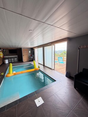 An indoor swimming pool with a view of the outdoors, a ceiling with recessed lighting, and a tiled floor.