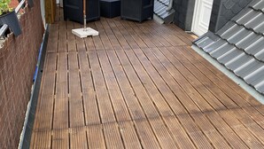 Une terrasse en bois avec des meubles d’extérieur et un grand parasol.