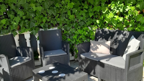 A patio area with wicker furniture, including two chairs and a small table, set on a stone floor. - Le Pastre (Montpeyroux)
