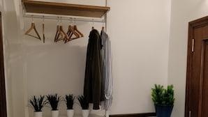 Un pasillo con un armario blanco, perchas de madera, un perchero y plantas en macetas.