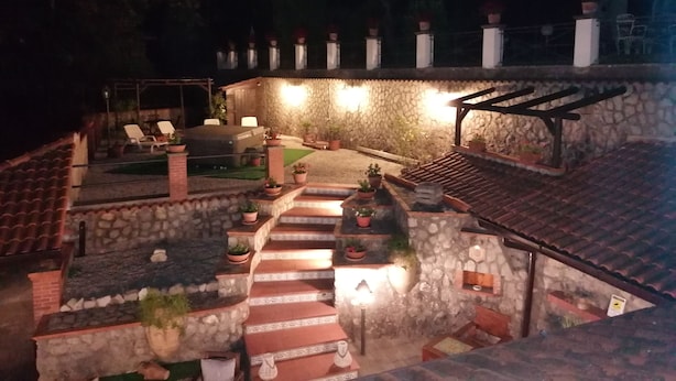 Un espacio al aire libre con paredes de piedra y una escalera que lleva a una zona de estar cubierta.