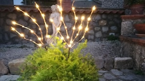 Un jardín con una estructura decorativa de luces y una estatua.