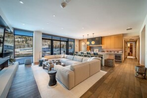 Relax in this spacious living room with a large sectional sofa, flat-screen TV, and dining area.