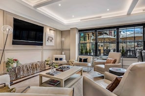 Relax in a spacious living room with a large flat-screen TV, comfortable seating area, and a coffee table with books and decorative items.
