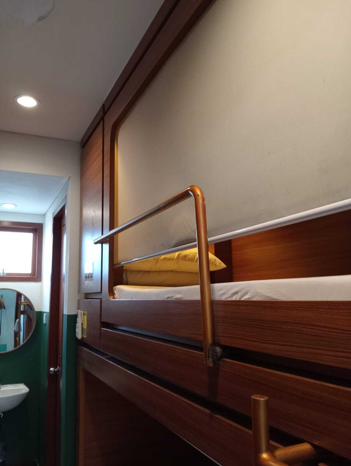 A bunk bed with a metal ladder, a small window, and a mirror.