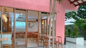 A restaurant with a pink exterior, wooden furniture, and a glass door with the name 'LIBERTAS'. - Liberta Malioboro South (Yogyakarta)