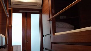 A compact, well-lit interior with a bunk bed, wooden cabinetry, and an air conditioning unit. - Liberta Malioboro South (Yogyakarta)