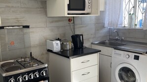 Eine kompakte Küche mit Gaskochfeld, Mikrowelle, Toaster, Waschmaschine und Spüle.