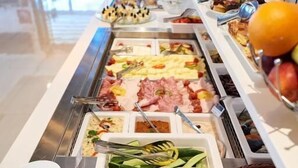 Buffet amb diverses opcions gastronòmiques, incloent carns, formatges i fruita.
