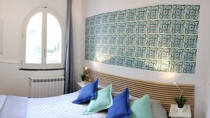 Un dormitorio con cama, almohadas, armario, radiador y una pared con diseño de azulejos.