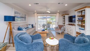 A living room with a sofa, two armchairs, a coffee table, and a TV. - Siesta Key 3BR Villa - Pool & Dock Access in Polynesian Gardens (Sarasota)