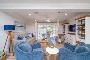 A living room with a sofa, two armchairs, a coffee table, and a TV.