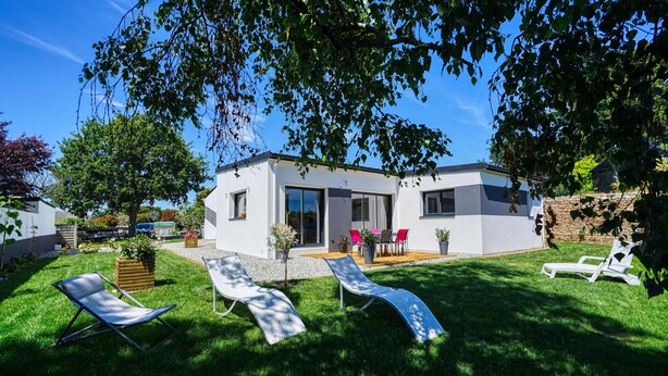 A modern house with a patio, two lounge chairs, and a small garden. - Jolie Maison Neuve, Très Bien Exposée, au Calme, Jardin, Terrasse (Sainte-Hélène)