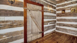 A rustic interior with a wooden door, exposed wooden walls, and a wooden floor.