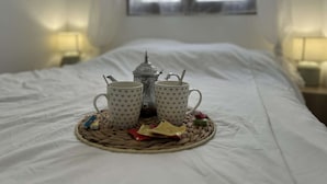 Una cama con sábana blanca, una lámpara de noche y una ventana con cortinas.