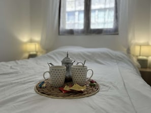A bed with a white sheet, a bedside lamp, and a window with curtains.