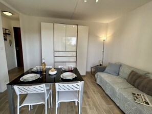 Uma sala de estar moderna com sofá, uma mesa de jantar com cadeiras e uma área de cozinha com armários.
