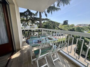 A balcony with a table and chairs, a view of the surrounding area, and a building in the background.