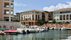 Un puerto deportivo con varias embarcaciones amarradas, rodeado de edificios de varios pisos con balcones.