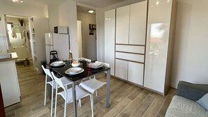 Un espacio habitable compacto con comedor, kitchenette y sofá.
