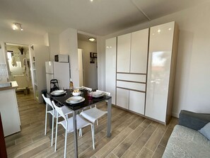 A compact living space with a dining area, kitchenette, and a sofa.