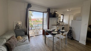 Un espacio habitable compacto con sofá, mesa de comedor, sillas, zona de cocina y balcón con vistas.