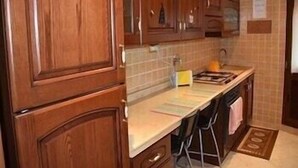 A kitchen with wooden cabinets, a countertop, and a sink. - Cleopatra (Rome)