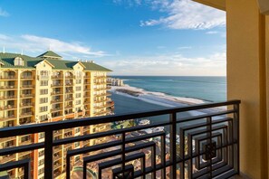 A hotel with multiple balconies overlooking a beach and ocean.