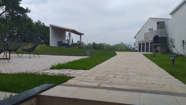 Un sendero conduce a un edificio con mesas al aire libre y una pérgola.