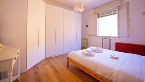 Ein Schlafzimmer mit einem Holzbett, einem weißen Kleiderschrank und einem Fenster mit Jalousien.