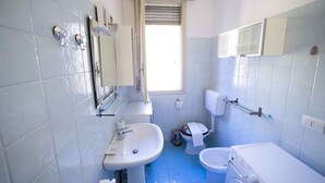 Ein kleines Badezimmer mit Waschbecken, Toilette und Waschmaschine.