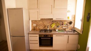Eine kleine Küche mit Kühlschrank, Backofen, Spüle und Holzboden.