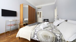 A hotel room with a bed, a TV, a mirror, a wardrobe, and a bedside table with a lamp. - GetTheKey appartamento Quadrilatero (Bologna)