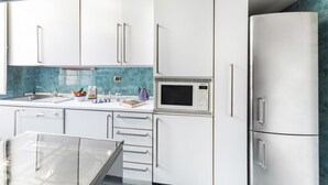 A modern kitchen with white cabinets, a built-in microwave, and a glass dining table. - GetTheKey appartamento Quadrilatero (Bologna)