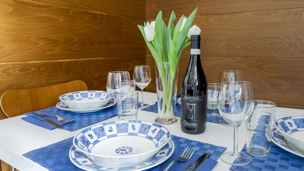 A dining table set with blue and white plates, a bottle of Barolo wine, and tulips in a vase. - GetTheKey appartamento Quadrilatero (Bologna)